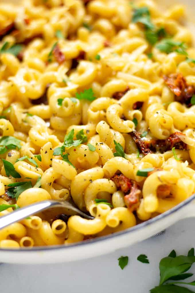 Close up shot of a pan filled with smoked gouda mac and cheese garnished with fresh parsley