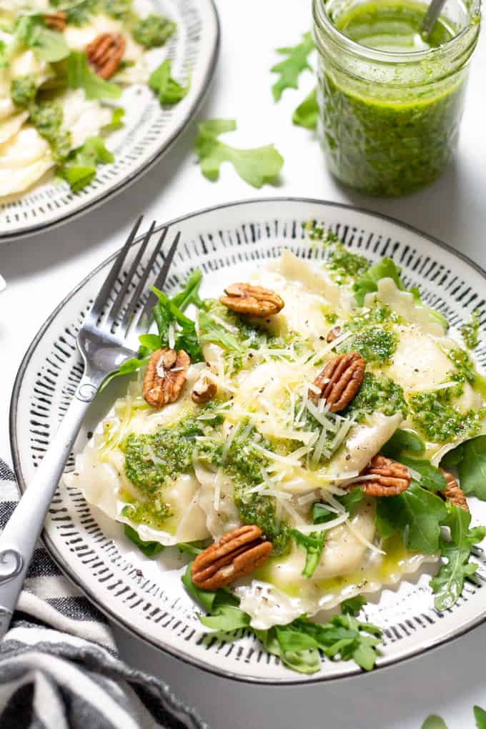 Close up shot of a white plate filled with wonton ravioli and arugula pesto