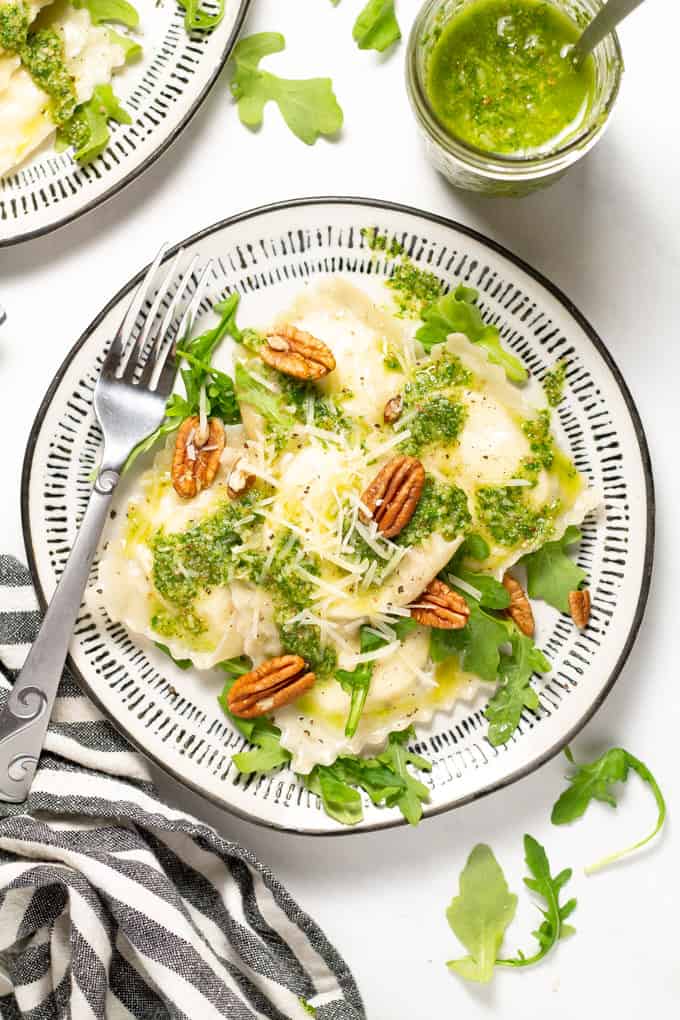 Overhead shot of a white plate filled with wonton ravioli and arugula pesto