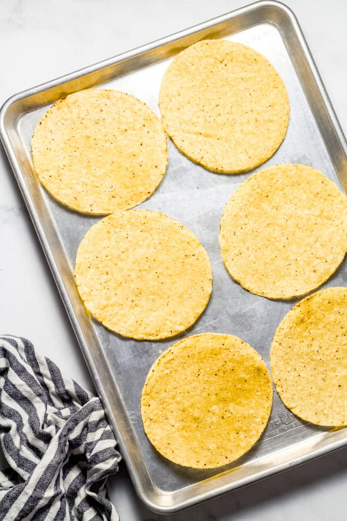 Metal sheet pan filled with tostadas getting ready to be put in the oven