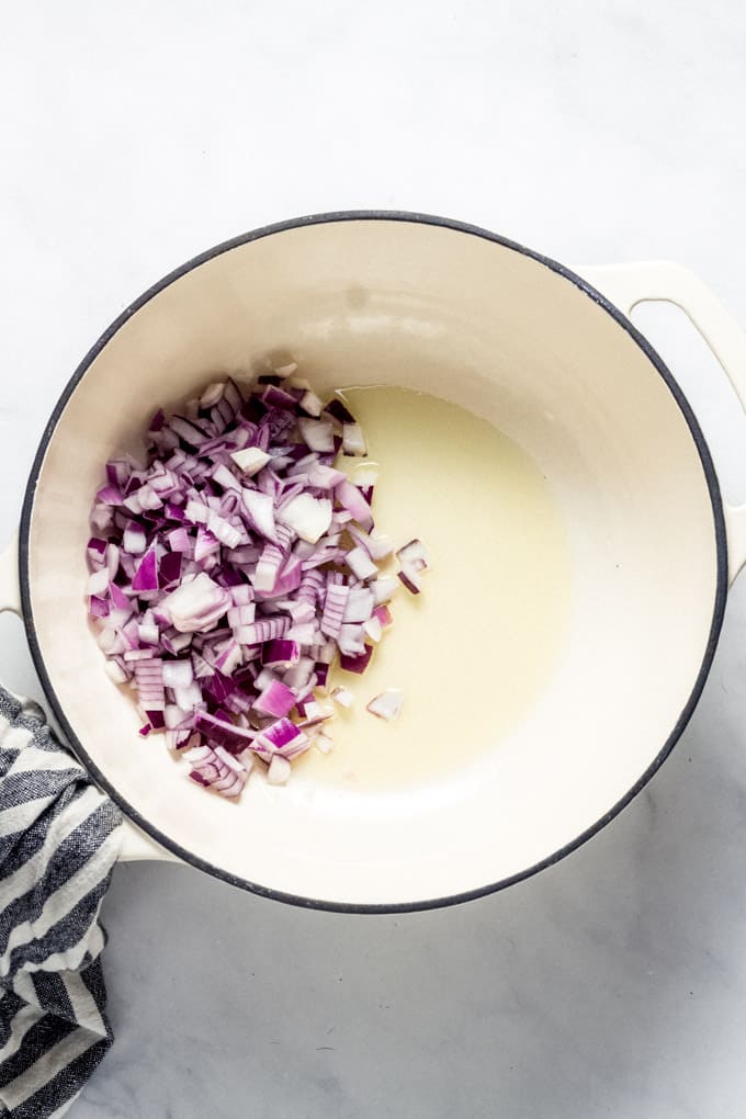 Overhead shot of a white pot filled with olive oil and onions