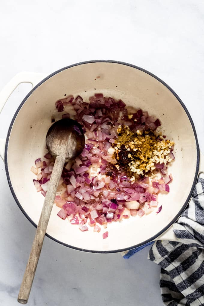 Overhead shot of a white pot with onions and spices in it