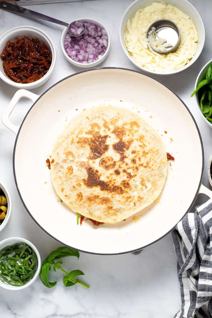 Overhead shot of a white pan filled with a Greek quesadilla freshly cooked