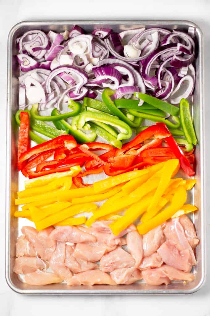 Sheet pan filled with chicken peppers and onions for sheet pan fajitas