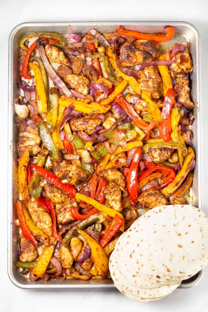 Sheet pan filled with chicken peppers and onions for sheet pan fajitas