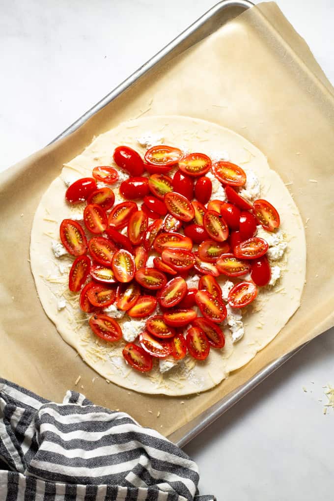 Pie crust topped with goat cheese Parmesan cheese and grape tomatoes