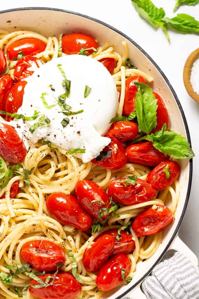 Overhead shot of a pan filled with tomato and garlic pasta garnished with fresh basil