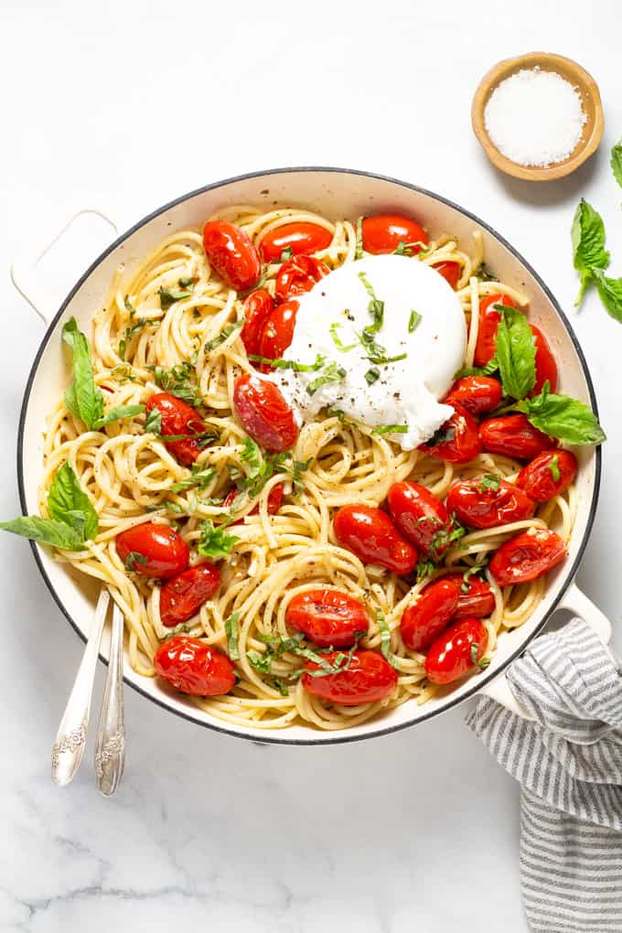 Overhead shot of a pan filled with tomato and garlic pasta garnished with fresh basil