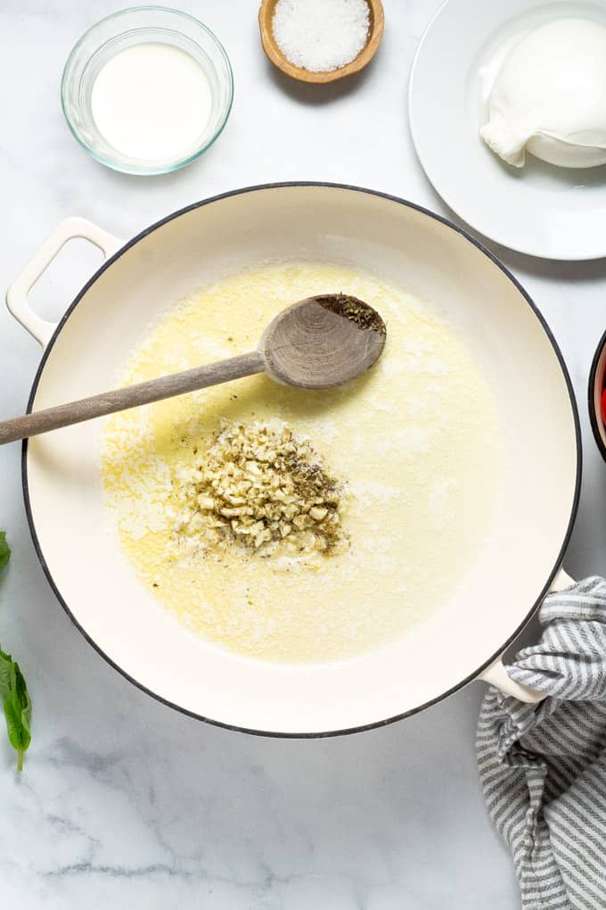 A pan with melted butter and a pile of minced garlic and dried oregano in it