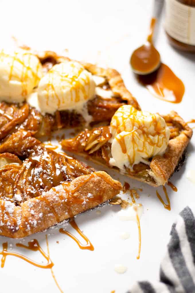 Close up shot of a slice of an apple tart topped with caramel and ice cream