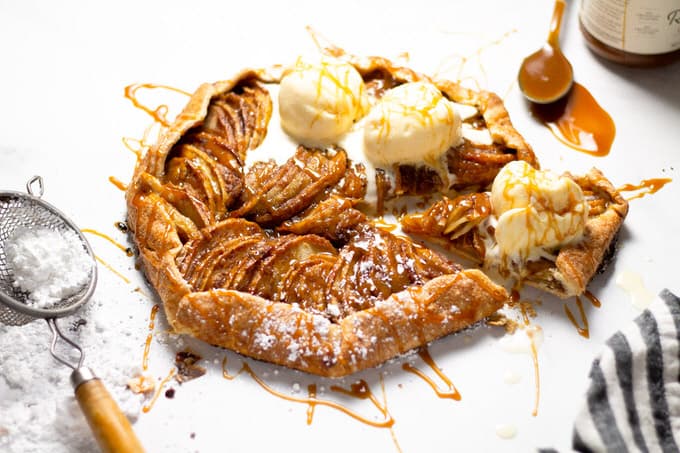 Close up shot of an apple tart topped with caramel and ice cream