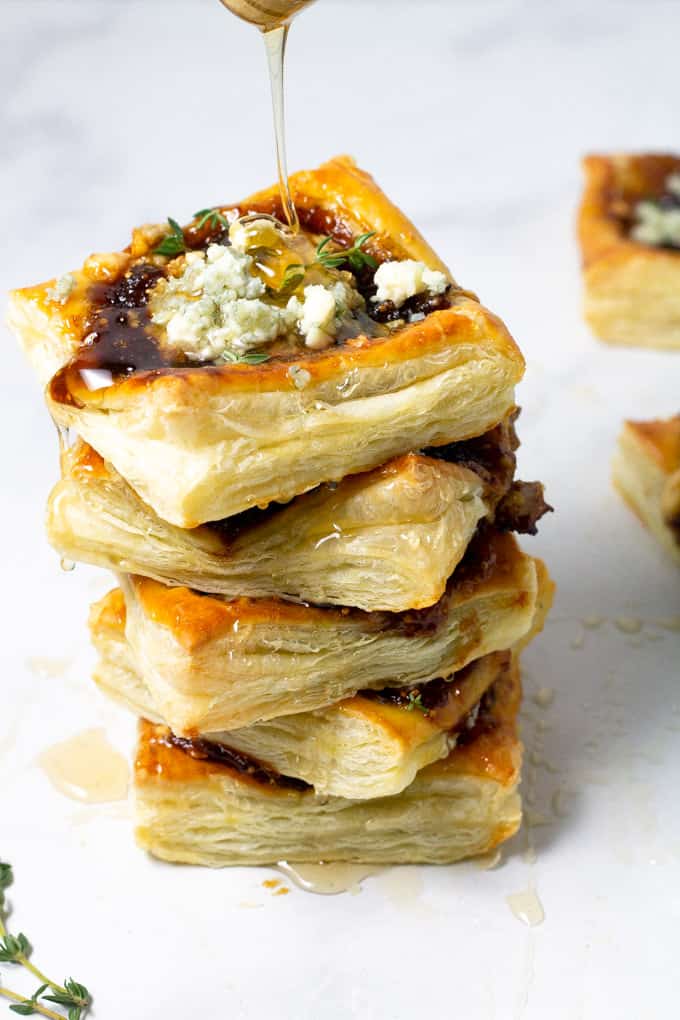 Close up shot of a tower of caramelized onion tarts being drizzled with honey