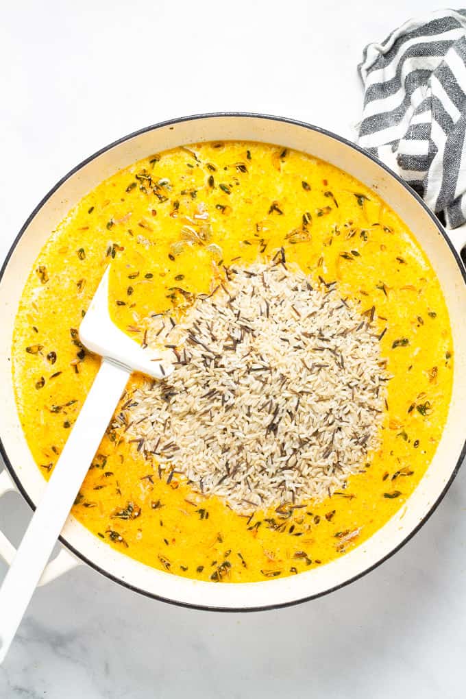 A large saute pan with veggies broth and cream stir together and wild rice just added on top