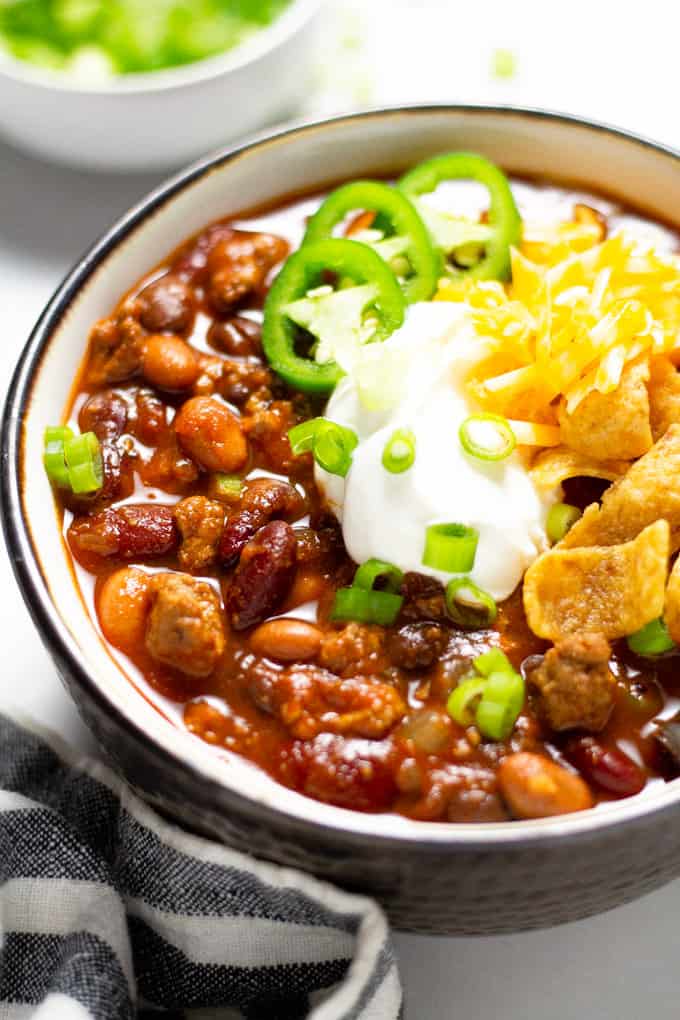 A close up shot of a bowl of slow cooker turkey chili garnished with sour cream