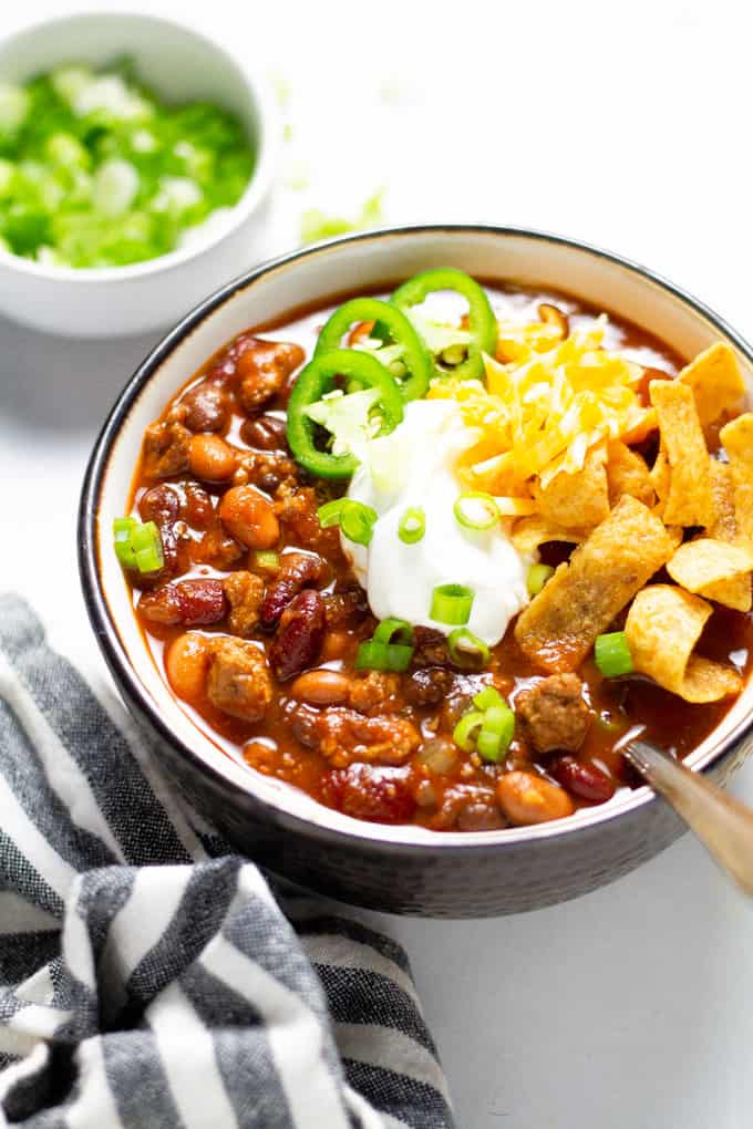 A close up shot of a bowl of slow cooker turkey chili garnished with sour cream