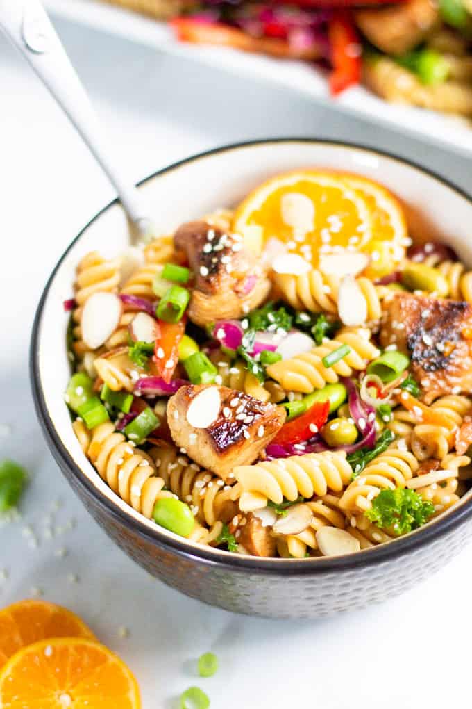 Black and white bowl filled with Asian Chicken Pasta Salad garnished with sesame seeds