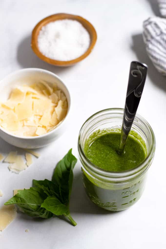 A mason jar of homemade basil pesto with a spoon in it