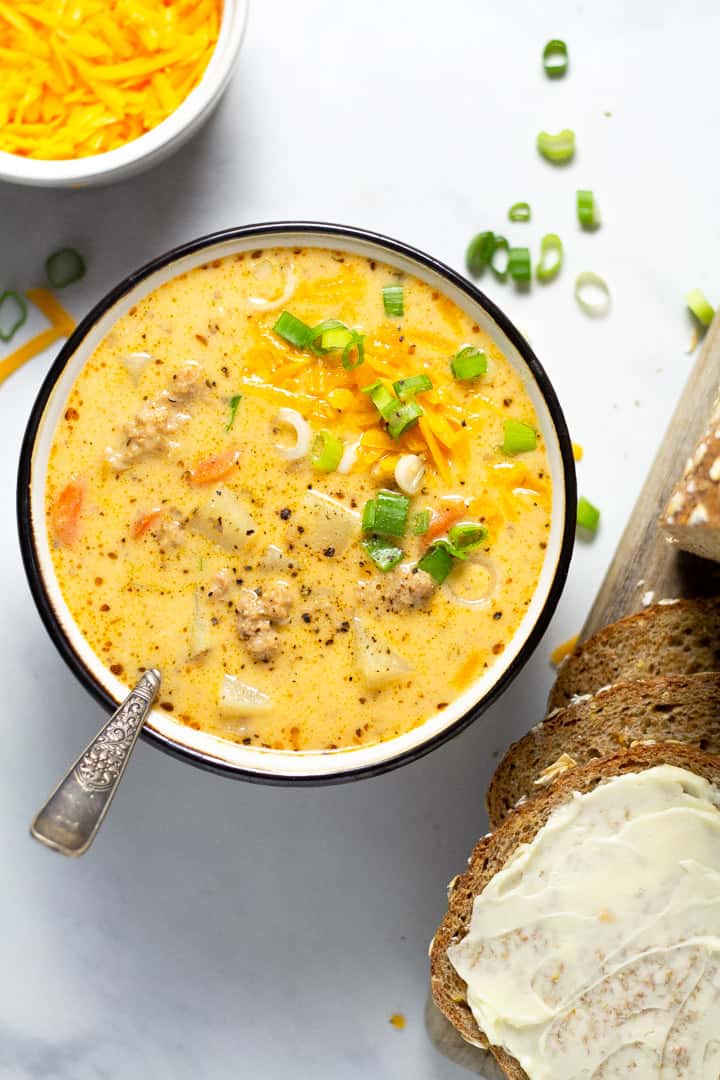 Overhead shot of a bowl filled with homemade beer cheese potato soup garnished with shredded cheddar cheese