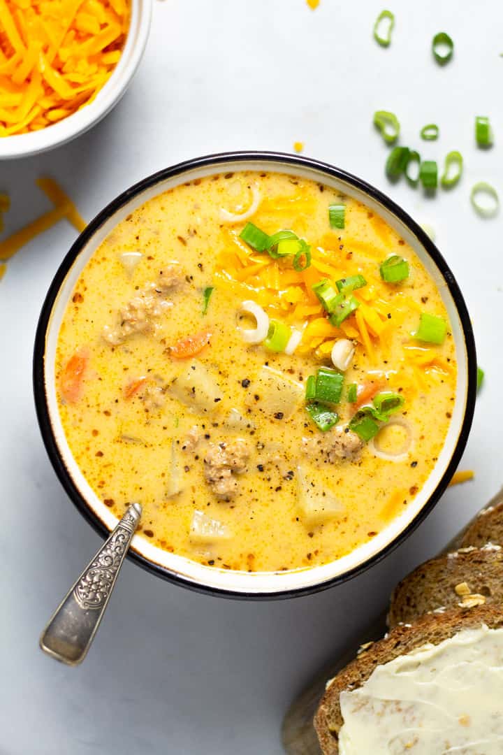 Overhead shot of a bowl filled with homemade beer cheese potato soup garnished with shredded cheddar cheese