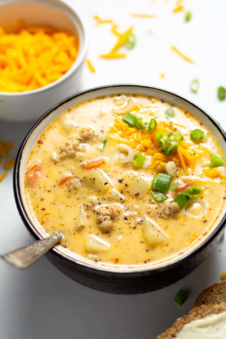Close up shot of a bowl filled with homemade beer cheese potato soup garnished with shredded cheddar cheese