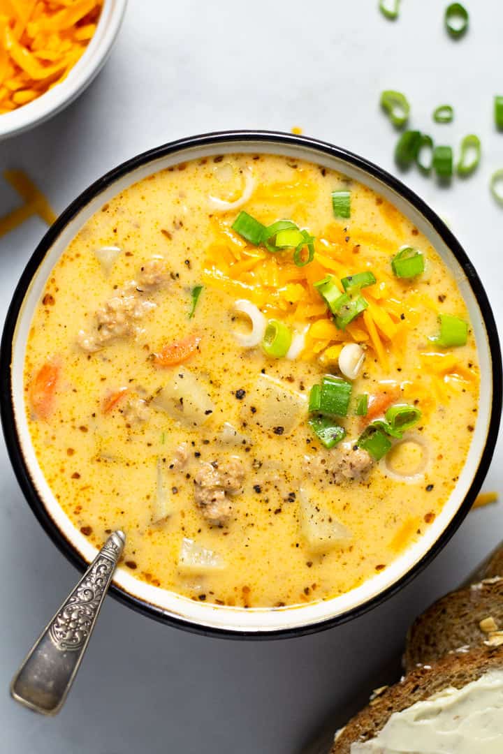 Overhead shot of a bowl filled with homemade beer cheese potato soup garnished with shredded cheddar cheese