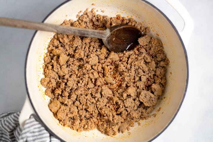White dutch oven filled with cooked spicy turkey sausage