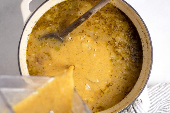 White dutch oven with creamy soup being poured into it