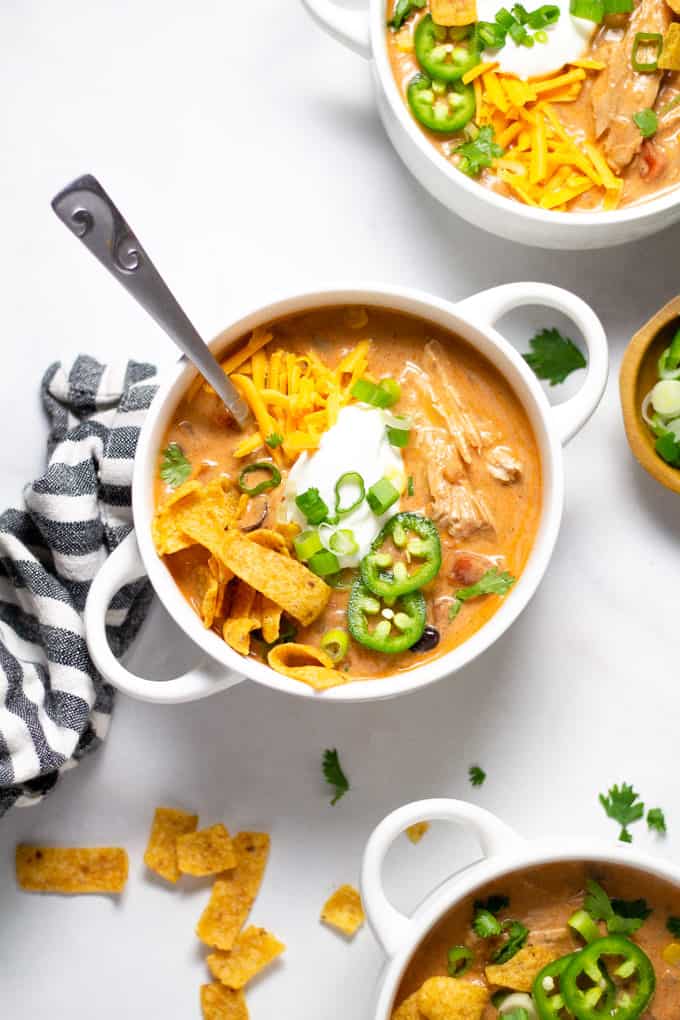 Overhead shot of a white bowl filled with slow cooker chicken chili garnished with sour cream and green onions