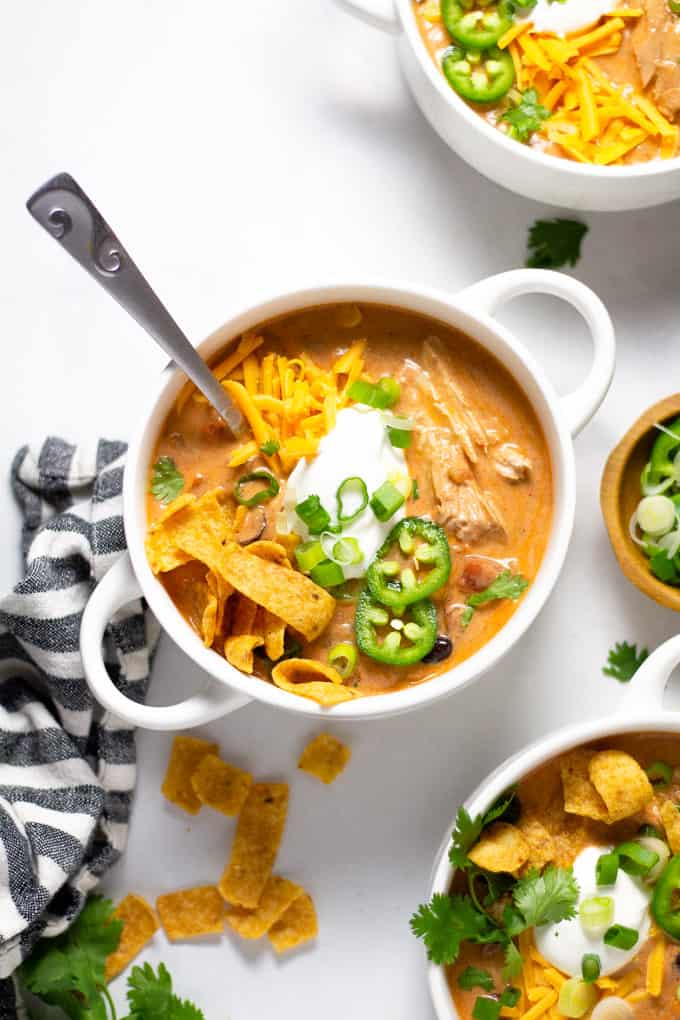 Overhead shot of a white bowl filled with slow cooker chicken chili garnished with sour cream and green onions