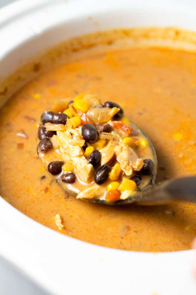 A spoon scooping slow cooker chicken chili out of the crock pot