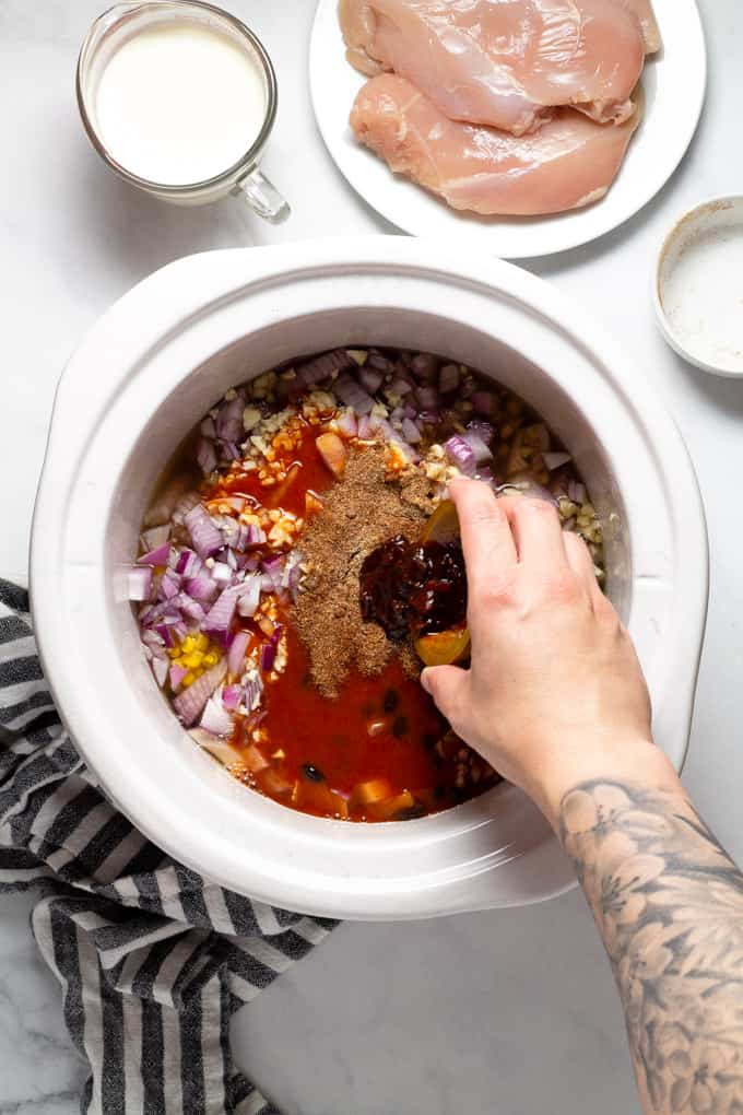 White slow cooker insert with ingredients to make slow cooker chicken chili