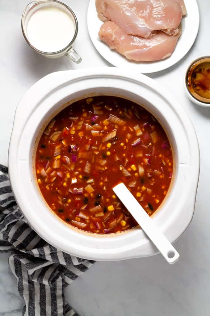 White slow cooker insert with ingredients to make slow cooker chicken chili