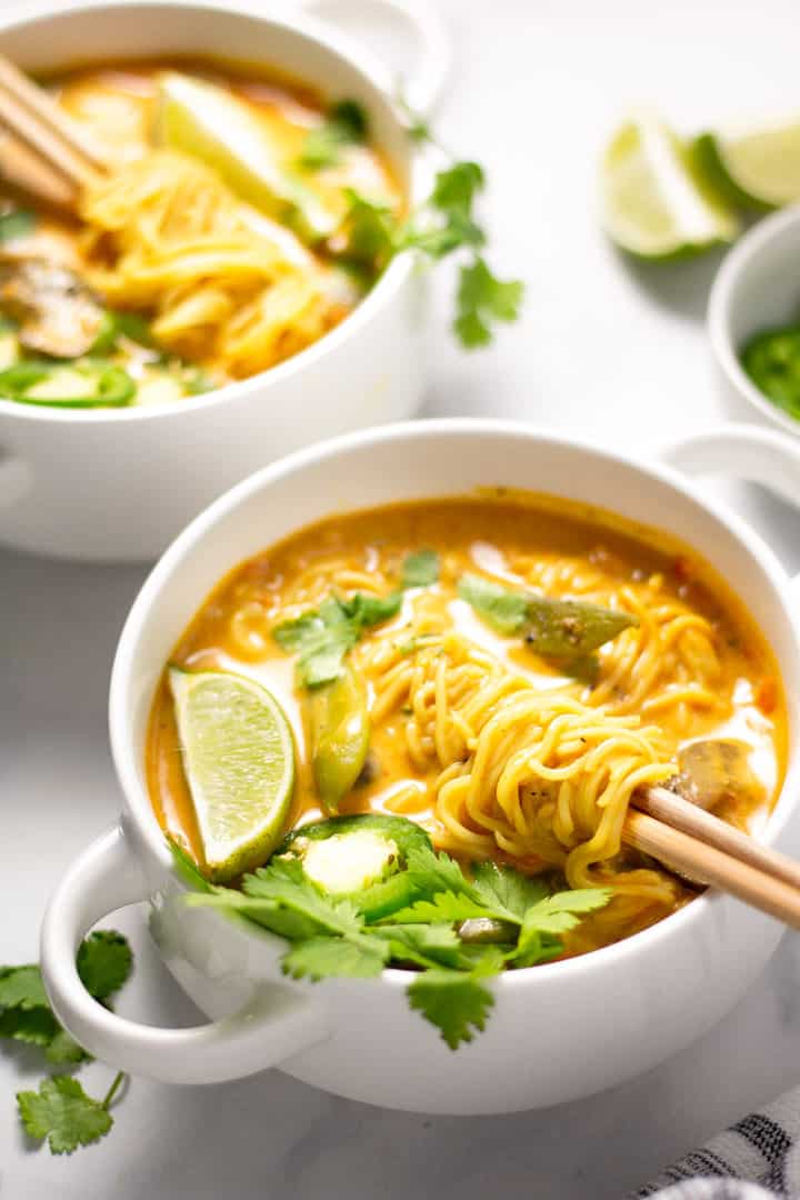 Two white bowls filled with vegan curry ramen garnished with fresh cilantro