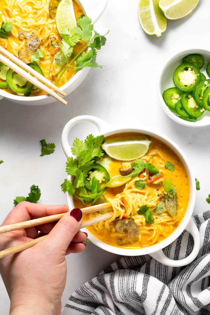 Two white bowls filled with vegan curry ramen garnished with fresh cilantro