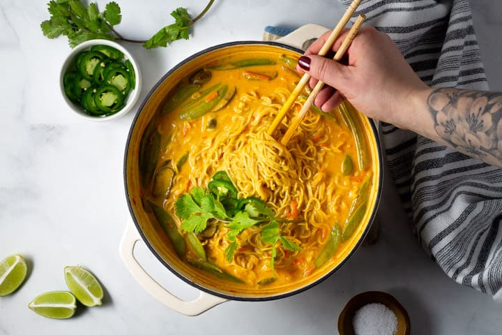 Overhead shot of a white dutch oven filled with vegan curry ramen noodles