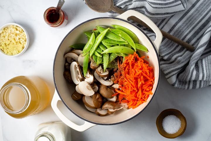 Overhead shot of a white dutch oven filled with ingredients to make vegan curry ramen noodles
