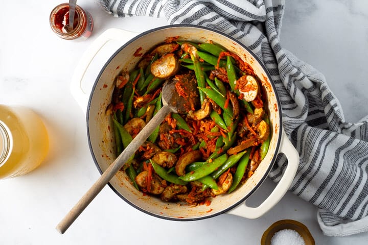 Overhead shot of a white dutch oven filled with veggies for making curry ramen noodles