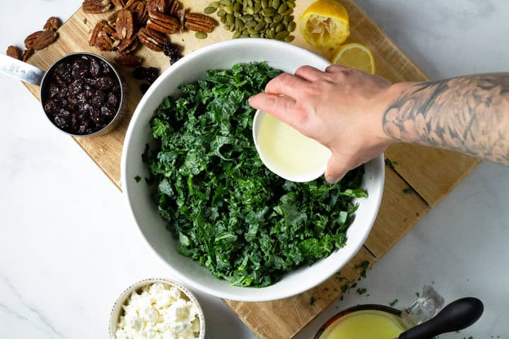Large bowl of chopped kale with olive oil being poured over it
