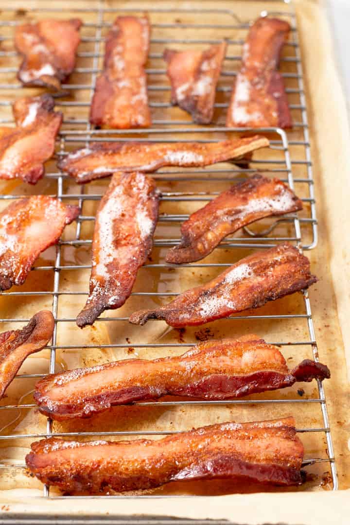 Parchment lined baking sheet with a cooling rack on it with cooked bacon on top of it