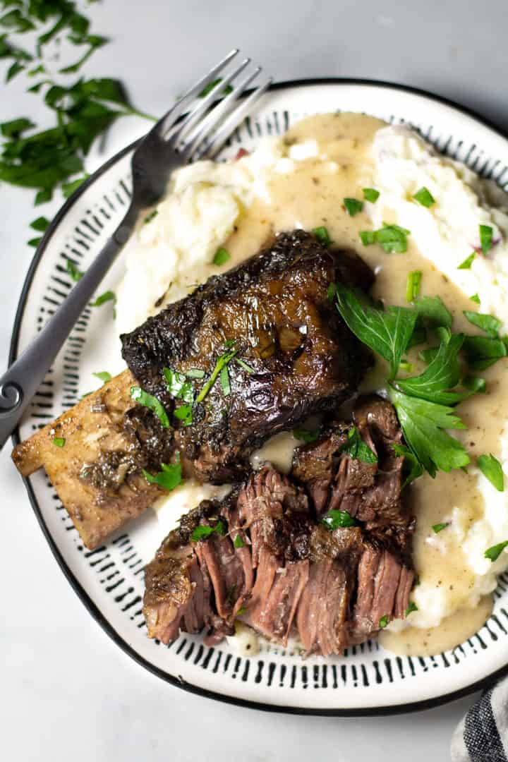 Overhead shot of a plate filled with short ribs and homemade mashed potatoes garnished with parsley