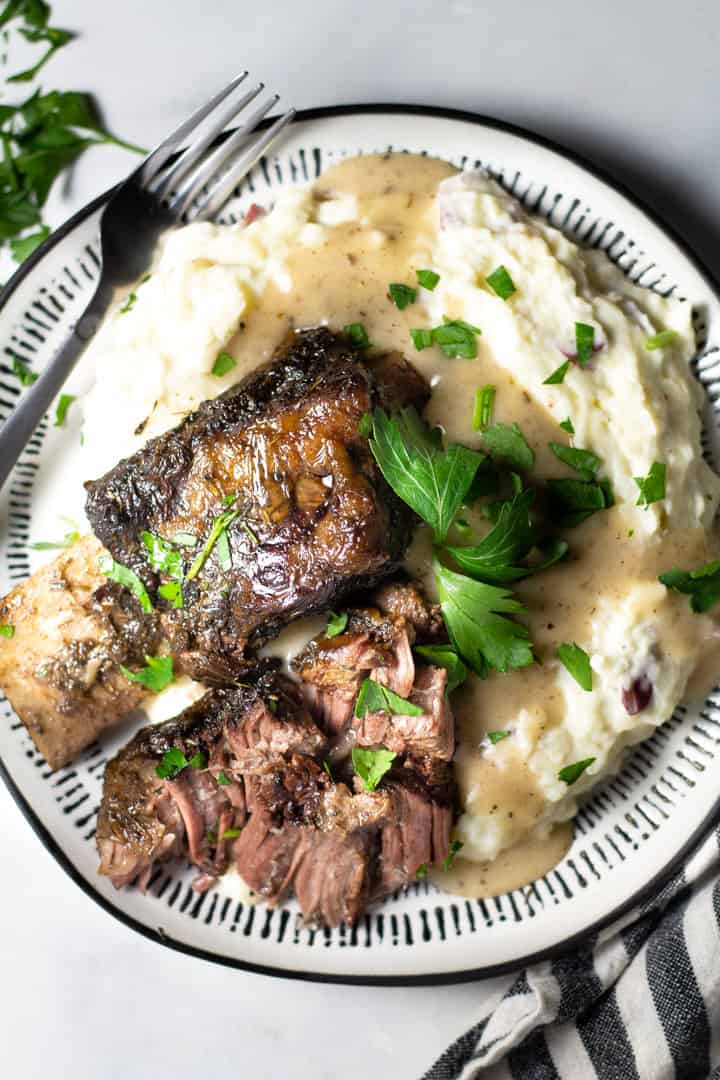 Overhead shot of a plate filled with short ribs and homemade mashed potatoes garnished with parsley