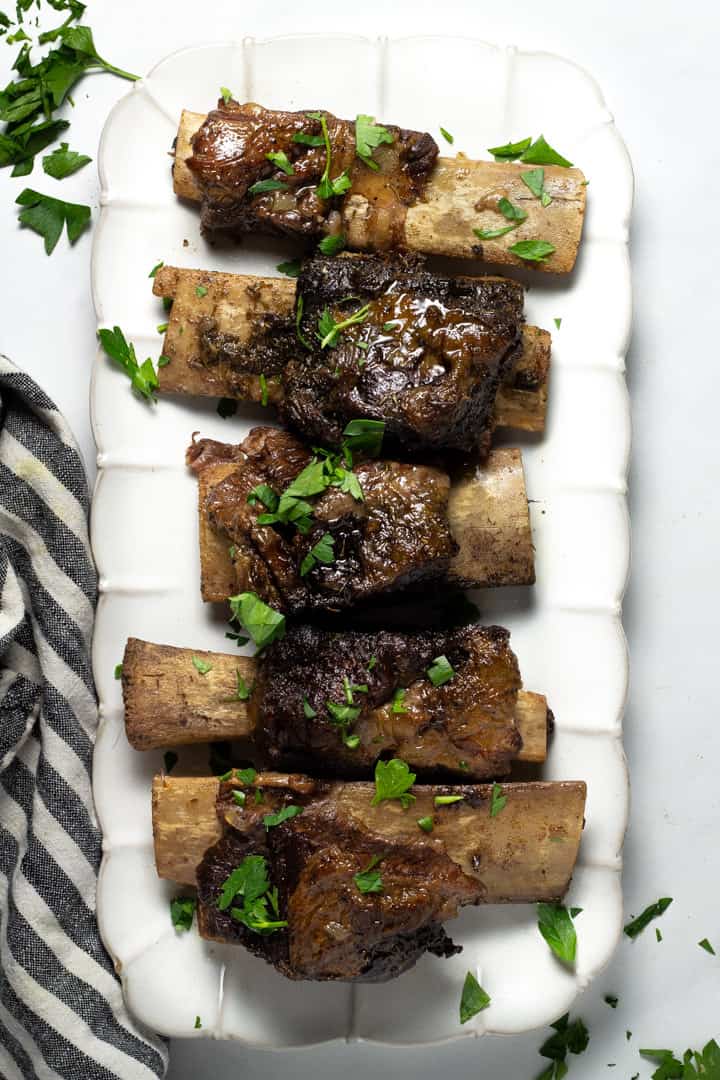 Overhead shot of a platter filled with short ribs garnished with fresh parsley
