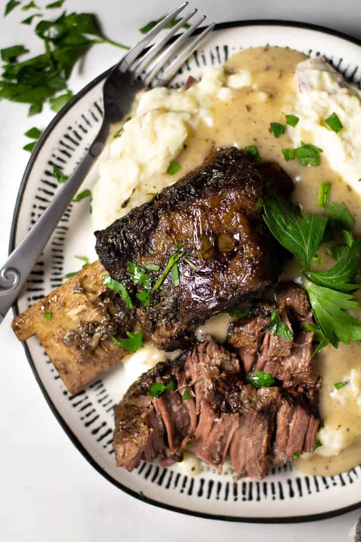 Overhead shot of a plate filled with short ribs and homemade mashed potatoes garnished with parsley