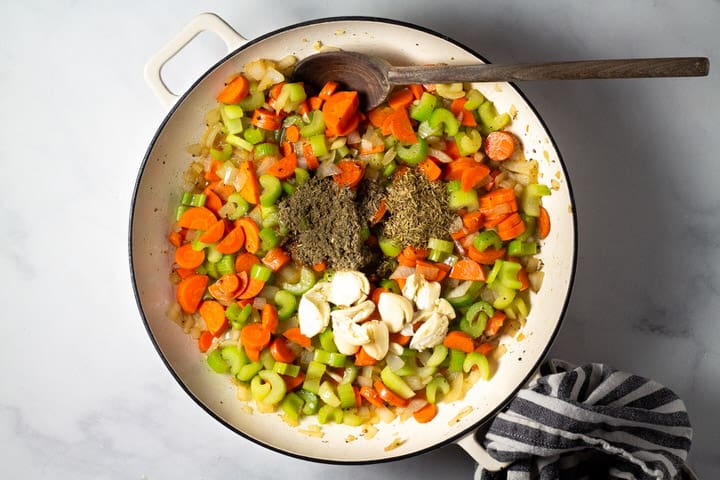 Large pot filled with carrots celery onion herbs and garlic