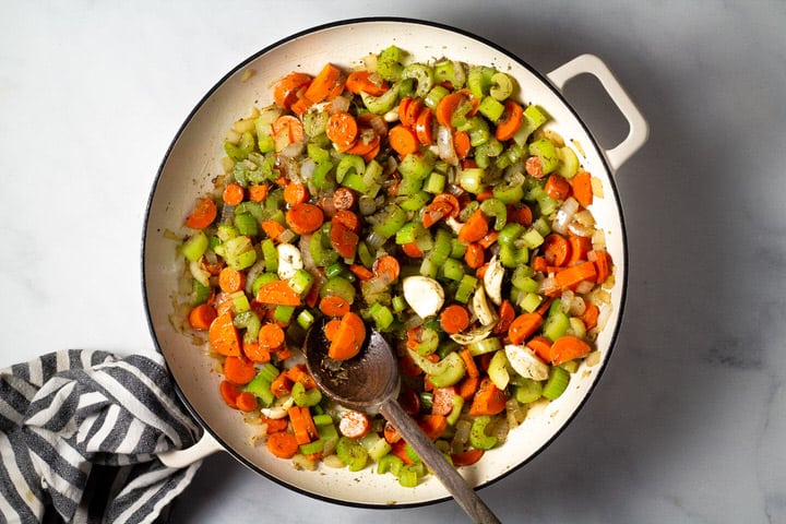 Large pot filled with carrots celery onion herbs and garlic
