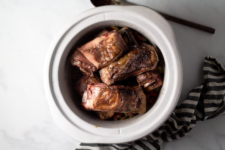 Large crock pot insert filled with seared short ribs