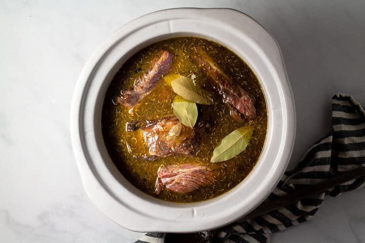 Large crock pot insert filled with seared short ribs and beer