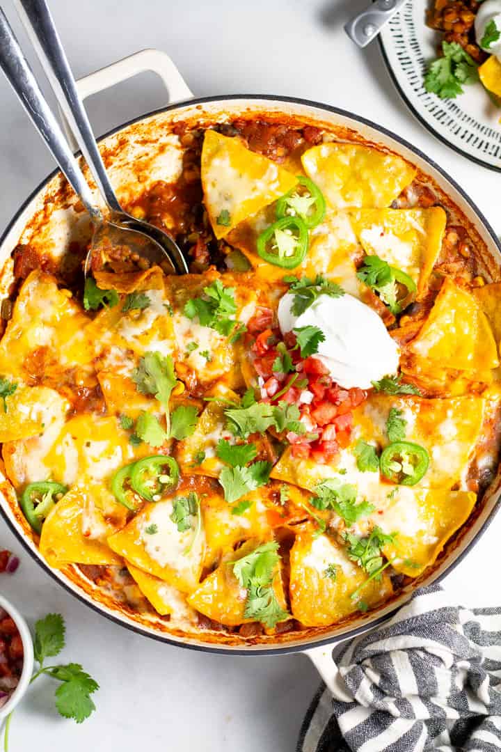 Overhead shot of a large skillet filled with vegetarian enchiladas garnished with fresh cilantro