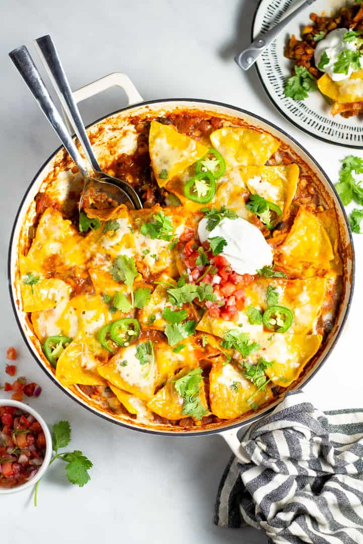 Overhead shot of a large skillet filled with vegetarian enchiladas garnished with fresh cilantro
