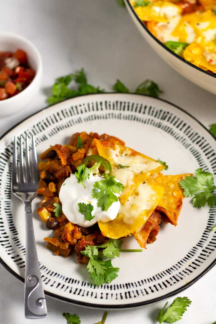 Close up shot of a white and black plate filled with skillet enchiladas